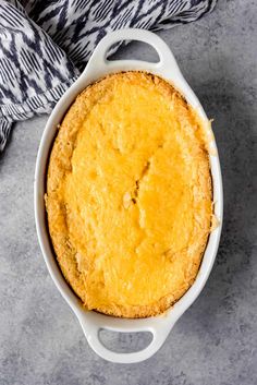 an overhead view of a cornbread casserole in a white dish on a gray surface