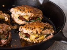 three hamburger patties in a skillet with melted cheese and herbs on the side