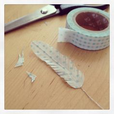 a pair of scissors next to a roll of tape and some paper birds on a table