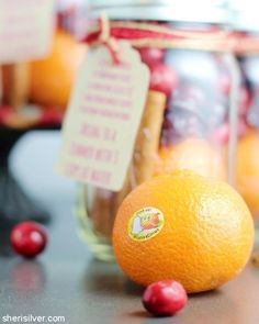 an orange sitting on top of a table next to a jar filled with cherries