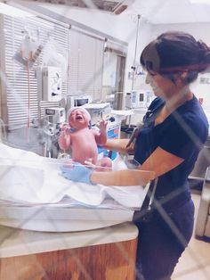 a woman holding a baby in an inclosure while standing next to a hospital bed