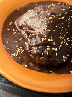 a chocolate dessert with sesame seeds on top in an orange bowl sitting on a blue cloth