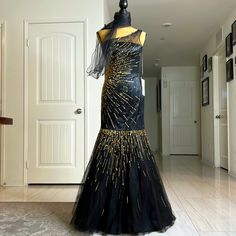 Gorgeous Mermaid Dress For Your Event. Fashioned With A One-Shoulder Design, This Beautiful Mermaid Gown In Black-Gold Exhibits An Appealing Pattern Of Sequins That Mimics The Look Of Gleaming Sun-Rays On The Torso And The Flared Floor-Length Skirt. The Sheer Shoulder Strap Extends To Blend Beautifully With An Asymmetrical Neckline And A Natural Waist For A Stunning Design. Size S Black Floor-length Mermaid Dress For Party Season, Black Embellished Mermaid Dress For Wedding, Black Mermaid Hem Dress With Sequins, Black Sequined Dresses With Mermaid Hem, Black Sequined Mermaid Hem Dress, Black Sequin Dress With Mermaid Hem, Fitted Black Embellished Mermaid Dress, Black Embellished Floor-length Mermaid Dress, Black Mermaid Hem Dress For Formal Occasion