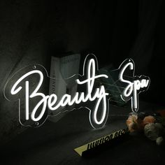 a neon sign that says beauty spa in white letters on a black background with a teddy bear