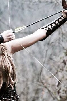 a woman with long hair is holding onto a bow and aiming it at the viewer