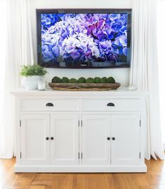 a flat screen tv sitting on top of a white cabinet