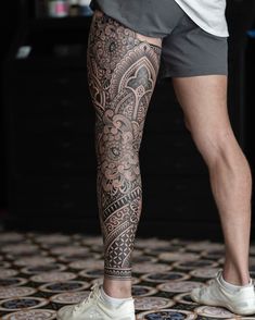 a man with tattoos on his legs and leggings is standing in front of a tiled floor