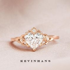 a heart shaped diamond ring on top of a white cloth