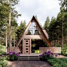 a - frame cabin in the woods with purple flowers and trees around it's entrance