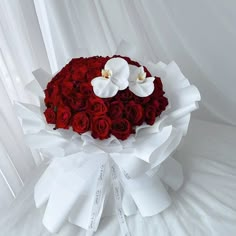 a bouquet of red roses and white orchids in the shape of a heart on a white background