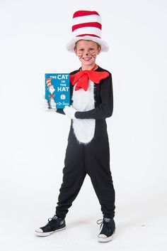 a young boy wearing a cat in the hat costume and holding a children's book