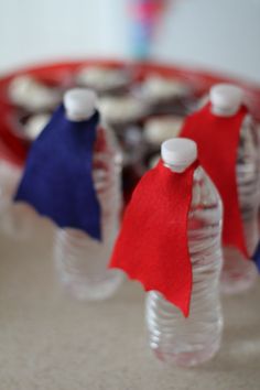 three plastic bottle caps with red, white and blue capes on them sitting on a table