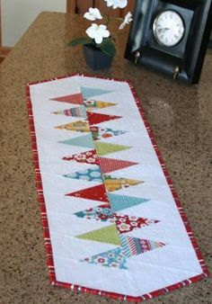 a table with a clock on it and a quilted runner in front of it