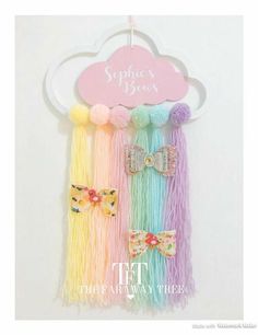 three colorful hair clips hanging on a white wall with a pink sign above them that says, spring is here