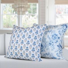 two blue and white pillows sitting on top of a couch