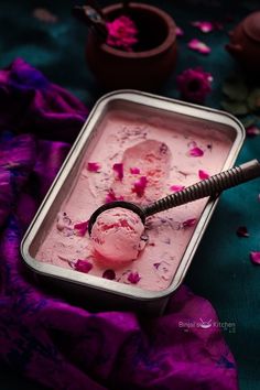 a scoop of ice cream in a metal container on a purple and blue table cloth