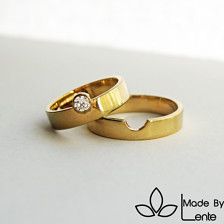 two gold wedding rings sitting on top of each other with a diamond in the middle