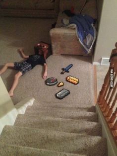 a little boy laying on the floor in front of a set of carpeted stairs