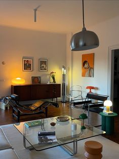 a living room filled with furniture next to a wall mounted light above a glass coffee table