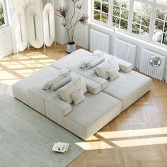 a large white couch sitting on top of a hard wood floor next to a window