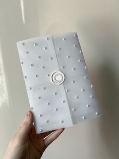 a person holding up a small white box with pearls on the front and bottom side