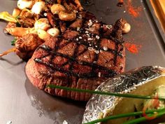 steak, potatoes and vegetables on a grill with some seasoning sprinkles