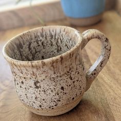 a brown and white cup sitting on top of a wooden table