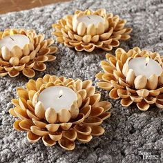 three candles are sitting on a gray blanket with two white ones in the shape of flowers