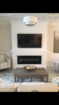 a living room with two couches and a television mounted on the wall above it