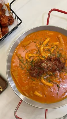 a bowl of soup with meat and vegetables in it on a table next to other dishes