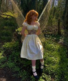 a woman dressed as a fairy standing in the woods