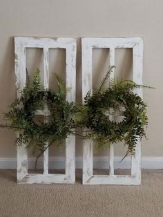 two white wooden frames with wreaths on them