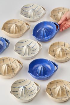 nine blue and white bowls with one hand reaching for the bowl, while another person holds it in their other hand