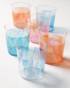 six glasses with different colored liquids in them