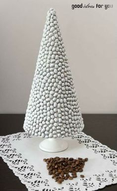 a small white tree on top of a doily with coffee beans in front of it