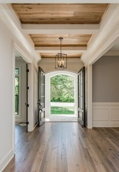 an open door leading into a large room with wood flooring and white trim on the walls