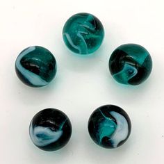 four marbles are arranged in a circle on a white surface, with one being blue and the other is green