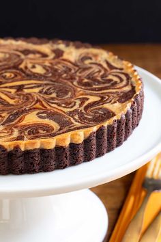 a chocolate cheesecake on a white cake plate