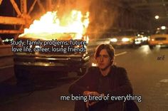 a man sitting on the side of a road next to a fire with words above it