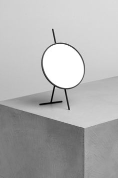 a black and white photo of a round light on top of a concrete block,