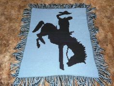 a crocheted blanket with a horse on it and fringes around the edges