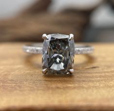 an engagement ring with a cushion cut diamond in the center on top of a wooden table