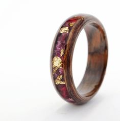 a wooden ring with red and gold flowers inlayed to the side on a white background