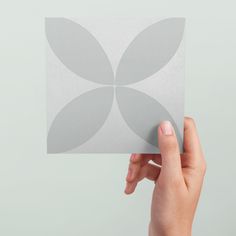 a person holding up a square piece of paper with circles on the back of it