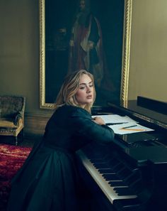 a woman sitting at a piano in front of a painting