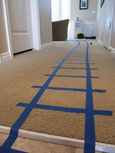 a room with blue tape on the floor that is taped to look like a train track