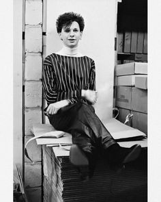 a black and white photo of a woman sitting on top of stacks of cardboard boxes