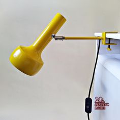 a yellow desk lamp sitting on top of a white wall