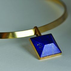 "Make: gold plated brass  Stone: undyed, natually mined Lapis Lazuli Stone dimensions: 2cmx2cm Choker circumference: 24.5cm without chain / 43 with chain / adjustable  The story of Mahkam is one of strength and resilience.  This collection is a deeply personal reflection of our individual journeys and transitions from the past to the future.  The work is inspired by the strength that was needed to persevere and make difficult choices - the strength to proclaim, \"I will live and carry on\".    W Gold Spiritual Pendant Choker, Spiritual Gold Pendant Choker, Gold Lapis Lazuli Spiritual Necklace, Gold-tone Brass Choker For Gift, Gold-tone Brass Choker As Gift, Modern Yellow Gold Choker For Gift, Modern Yellow Gold Choker As Gift, Gold Lapis Lazuli Jewelry Gift, Gold Lapis Lazuli Jewelry For Gift