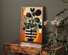 a painting on a table next to a vase with flowers in it and a potted plant